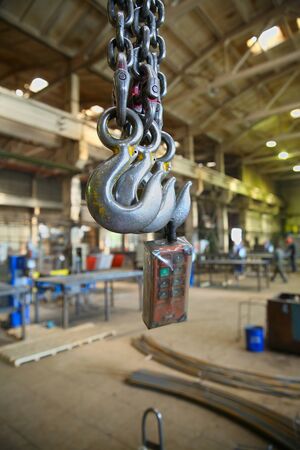 The steel hooks hanging on the background of industrial premisesの写真素材