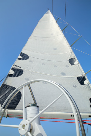 The mast, sail and rudder of the yacht on the background of blue skyの写真素材