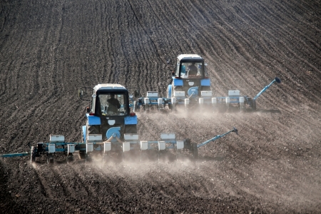 Blue tractors with sowers on the field in bright sunny spring morningの写真素材