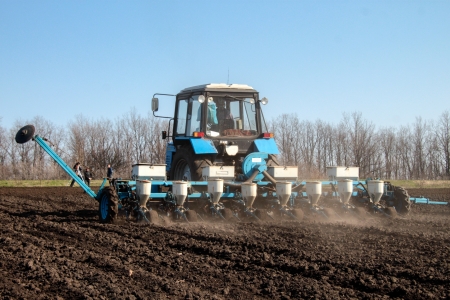 Blue tractor with sower on the field in bright sunny spring morningの写真素材
