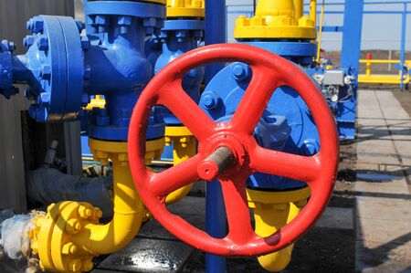 Red faucet with steel pipe in natural gas treatment plant in bright sunny summer dayの写真素材