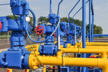 Red faucet with steel pipe in natural gas treatment plant in bright sunny summer dayの写真素材