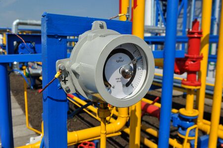 Pressure meter with yellow pipes in natural gas treatment plant in bright sunny summer dayの写真素材