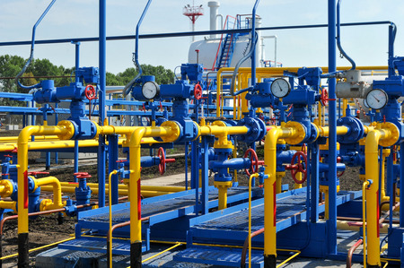 Pressure meter and red faucet with steel yellow pipe in natural gas treatment plant in bright sunny summer dayの写真素材