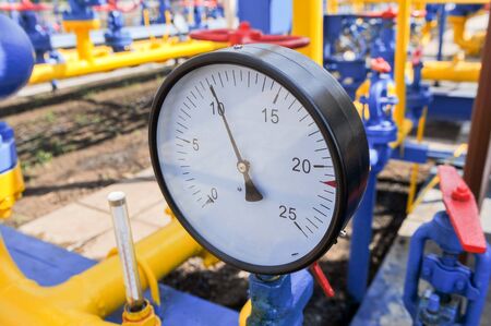 Pressure meter and red faucet with steel yellow pipe in natural gas treatment plant in bright sunny summer dayの写真素材