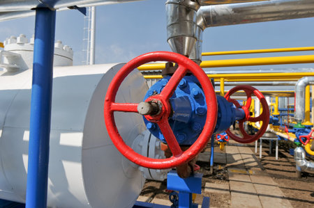 Red faucet with steel pipe in natural gas treatment plant in bright sunny summer dayの写真素材