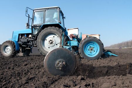 Blue tractor with sower on the field in bright sunny spring morningの写真素材