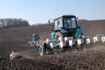 Blue tractor with sower on the field in bright sunny spring morningの写真素材