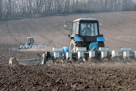 Blue tractor with sower on the field in bright sunny spring morningの写真素材