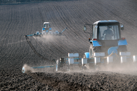 Blue tractor with sower on the field in bright sunny spring morningの写真素材
