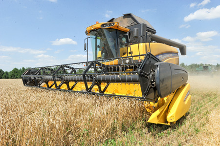 CHUGUEV, KHARKIV OBLAST, UKRAINE - JULY 24, 2015: Combine harvests wheat on a field in sunny summer day, 24 July 2015, Kharkiv Oblast, Ukraine.のeditorial素材