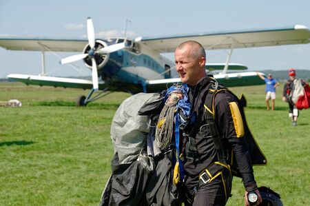 Kharkiv, Ukraine - August 20, 2016: Skydiver carries a parachute on background of Antonov An-2 aircraft  after landing at the airfield Korotych, Kharkov region, Ukraine on August 20, 2016のeditorial素材
