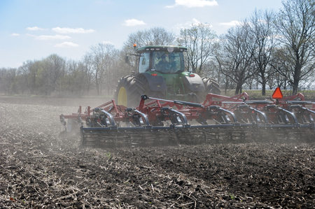 Kharkiv, Ukraine - April 13, 2017: Tractor with trailed planter working in field in a sunny spring day in Kharkiv Oblast, Ukraine on April 13, 2017のeditorial素材