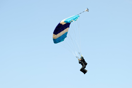 Paraglider flying on colorful parachute in blue clear sky at a bright sunny summer day. Active lifestyle, extreme hobbiesの写真素材