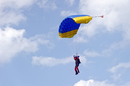 Paraglider flying on colorful parachute in blue clear sky at a bright sunny summer day. Active...