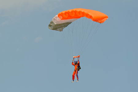 Paraglider flying on colorful parachute in blue clear sky at a bright sunny summer day. Active lifestyle, extreme hobbiesの写真素材