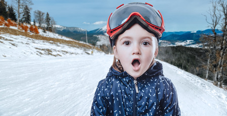 Funny kid girl in ski gear on winter backgroundの写真素材