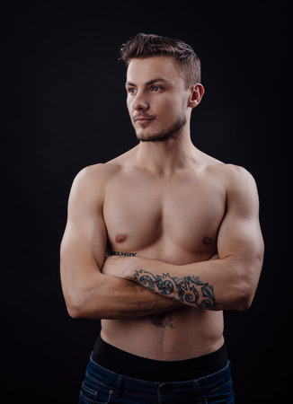 Image of handsome body guy with tatoo on arm on dark backgroundの写真素材