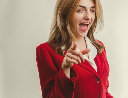 Attractive business lady in red jacket pointing finger forwardの写真素材