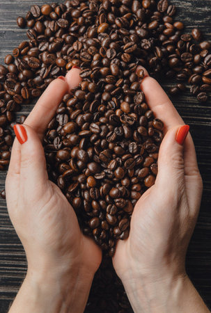 Female hands holding coffee beans in shape of heartの写真素材