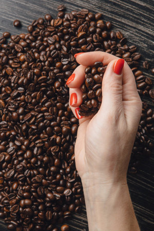 Female hands holding coffee beans in shape of heartの写真素材