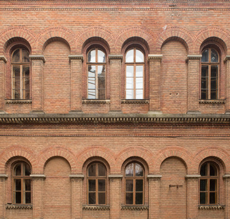 Old red brick wall with windows backgroundの写真素材