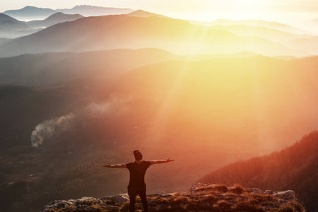 Man on top of mountain celebrating succes. Trip concept.の写真素材