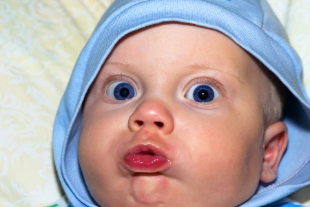Portrait of open-eyed 6-months old baby boy in hood.の写真素材
