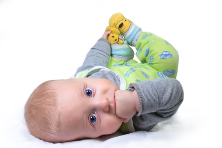 Six months old baby boy lying on his back, on the white bed.の写真素材