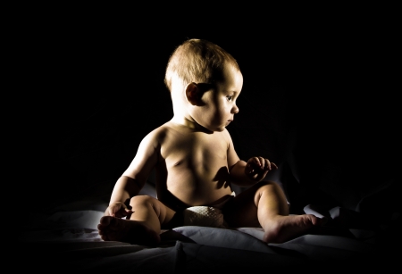 Eight month boy sitting on black background.の写真素材