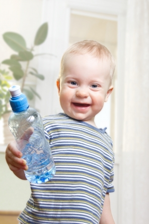 Portrait of year-old boy in striped t-shirt, holding a bottle of water.の写真素材