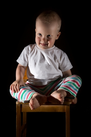Baby boy (1 year) sitting on chair, dark  background.の写真素材