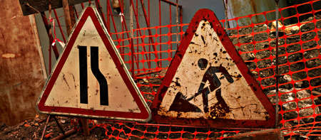 Grungy road signs  road narrows and road works on damaged road                               の写真素材