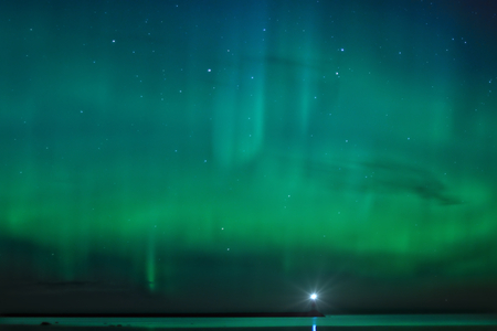 Night landscape with Aurora Borealis over the Ladoga Lake and a lighthouseの写真素材