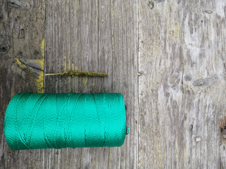 new bobbin of kapron thread for sewing on a gray wooden surface in the lower left corner shot by a...