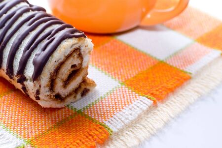 Chocolate tasty roll and orange cup on napkinの写真素材