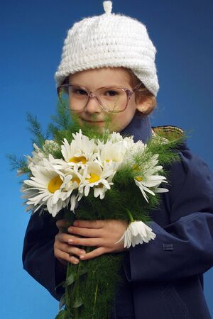 Little beautiful girl with flowers at blue backgroundの写真素材