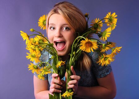 Pretty girl posing mouth open with yellow flowersの写真素材