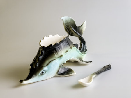 Caviar bowl with a spoon in the shape of a sturgeon on a white background. Specialized original dishes.の写真素材