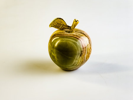 Apple shape onyx with golden leaf on white background. Souvenir and gift close-up.