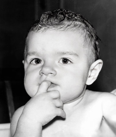 Vintage portrait of a cute little girl with a finger in her mouth. Retro photo from 1994.の写真素材