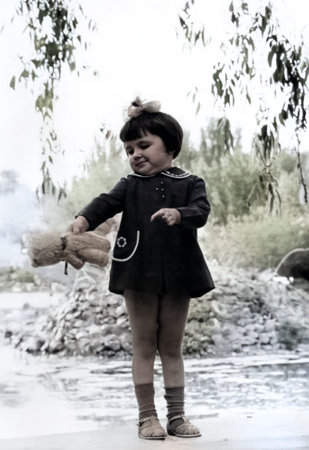 Vintage portrait of a little girl with a toy in her hands in the park. Retro photo from 1972.の写真素材