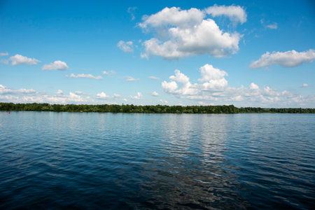 Panoramic view of the Dnieper river bank from embankment of the city of Dnieper. Reflection of the sky with clouds on the surface of the water.の写真素材