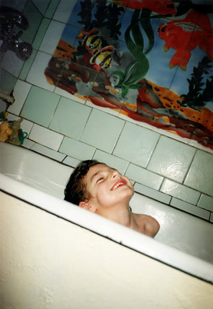 Vintage portrait of a girl child bathing in a bathtub. The child is smiling. Retro 1999.の写真素材