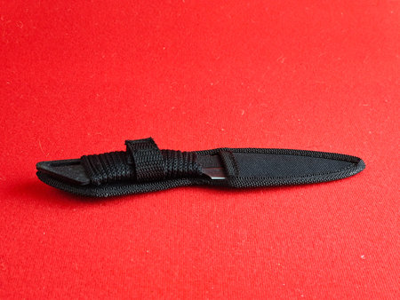 Throwing knife scorpion in a case. Traditional Japanese cold weapon on a red background.
