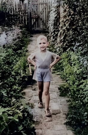 Vintage portrait of a smiling little boy running through a garden. Retro photo, 1963.の写真素材