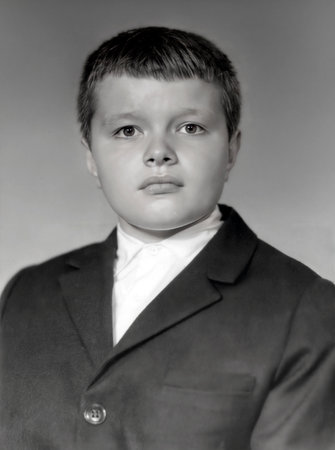 A vintage portrait of a serious-looking schoolboy wearing a jacket and white shirt. Retro photo from the 1960s.の写真素材
