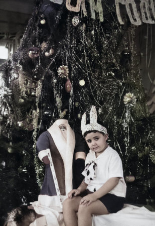 Dnepropetrovsk, Ukrainian SSR, USSR - January 1, 1964: Vintage portrait of a cute little boy in a New Year's bunny costume next to a Christmas tree. Retro photo.のeditorial素材