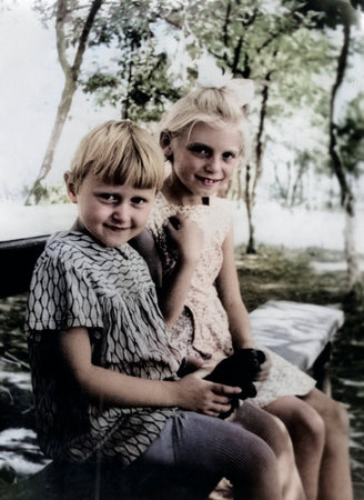 Lozovaya, Ukrainian SSR, USSR - July 11, 1965: Vintage portrait of two little girls sitting on a bench in a garden. Retro photo.のeditorial素材