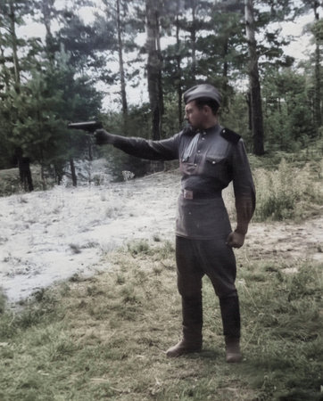 A vintage portrait of a young lieutenant during marksmanship training. The soldier holds a gun....